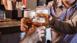 Amigos fazem brinde com caneca de cerveja em bar