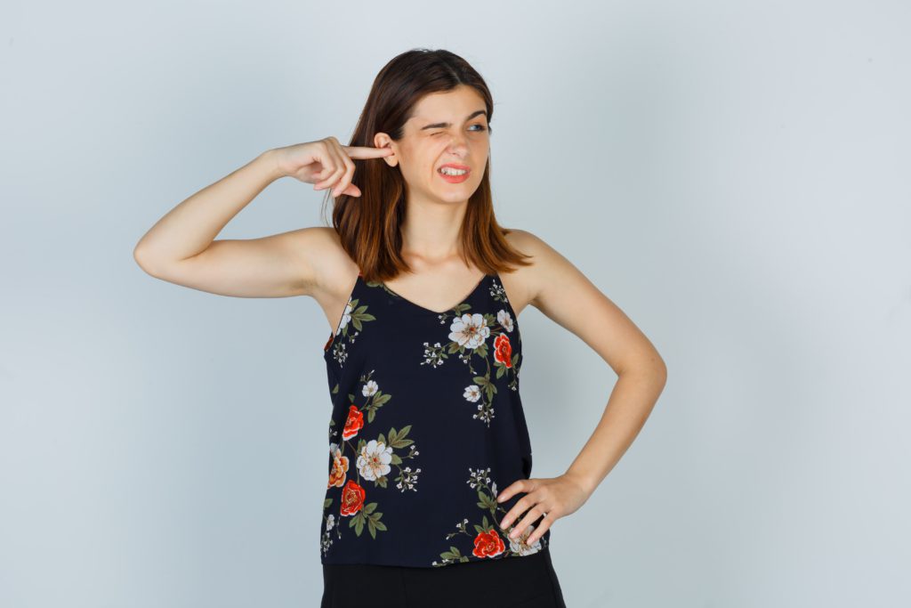 Mulher cutuca o ouvido com o dedo expressando incômodo