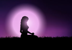 Imagem da silhueta de uma mulher posando em um campo. Sua sombra contrasta com o fundo em tons de roxo e lilás – proteção espiritual e energética.