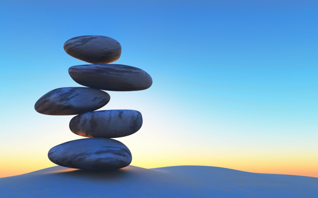 Pedras equilibradas uma em cima da outra com paisagem de por do sol ao fundo