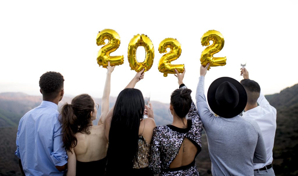Amigos comemoram no alto de uma montanha e levantam balões em formato de números que formam 2022